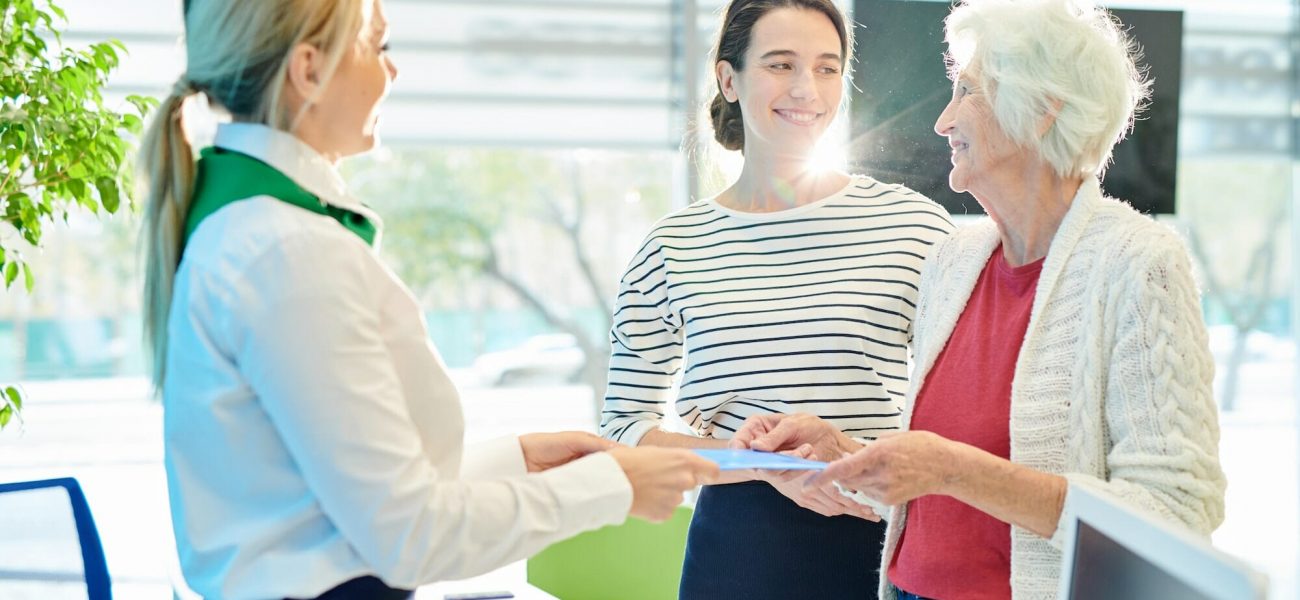Bank manager giving folder with documents to old lady