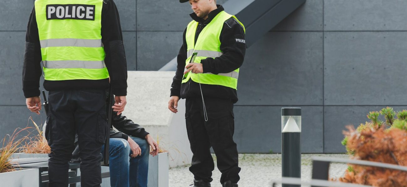 Two police officers talking to man on the street